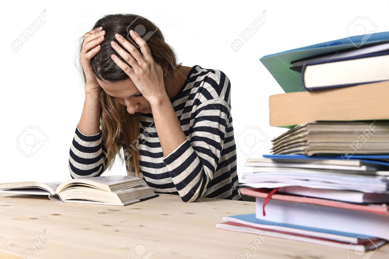 36900502 young stressed student girl studying pile of books on library desk preparing mba test or exam in str Stock Photo